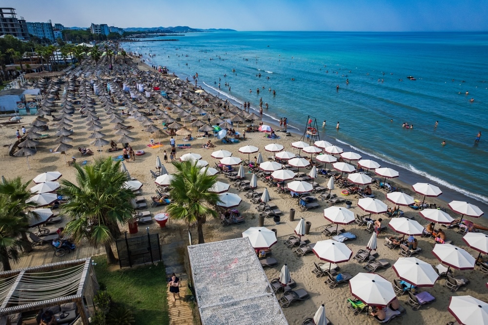 Široka peščena plaža v letovišču Golem pri Durrësu z urejenimi hotelskimi kompleksi in kristalno čistim morjem.