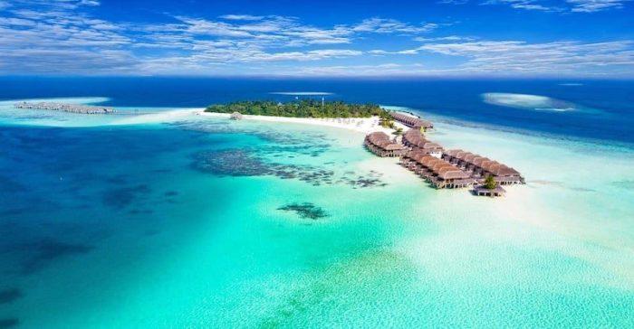 Turkizno morje in peščena plaža na Maldivih ob hotelskem resortu