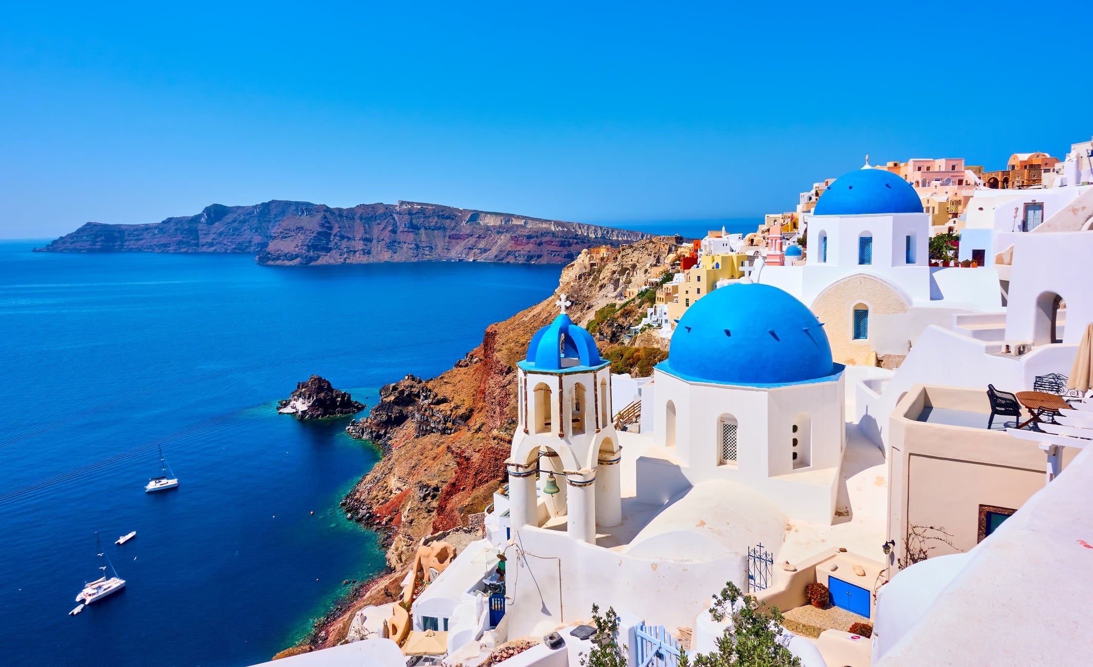 Santorini z belimi hišami in modrimi strehami nad morjem, priljubljen enodnevni izlet s Krete