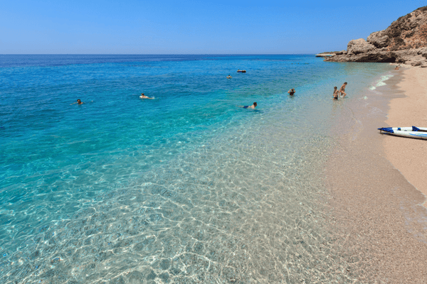 Moderna plaža Drymades z belimi kamenčki, turkizno vodo in trendovskimi beach bari na albanski rivieri.