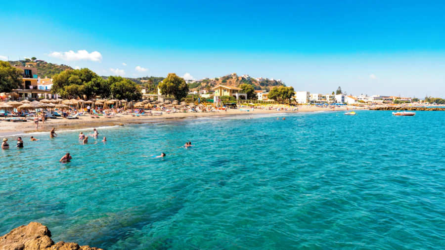 Sproščena plaža Aghia Marina z otokom Theodorou v ozadju