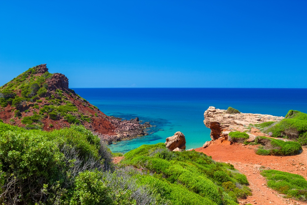 Menorca z zalivom, svetlim peskom in prozorno morsko vodo