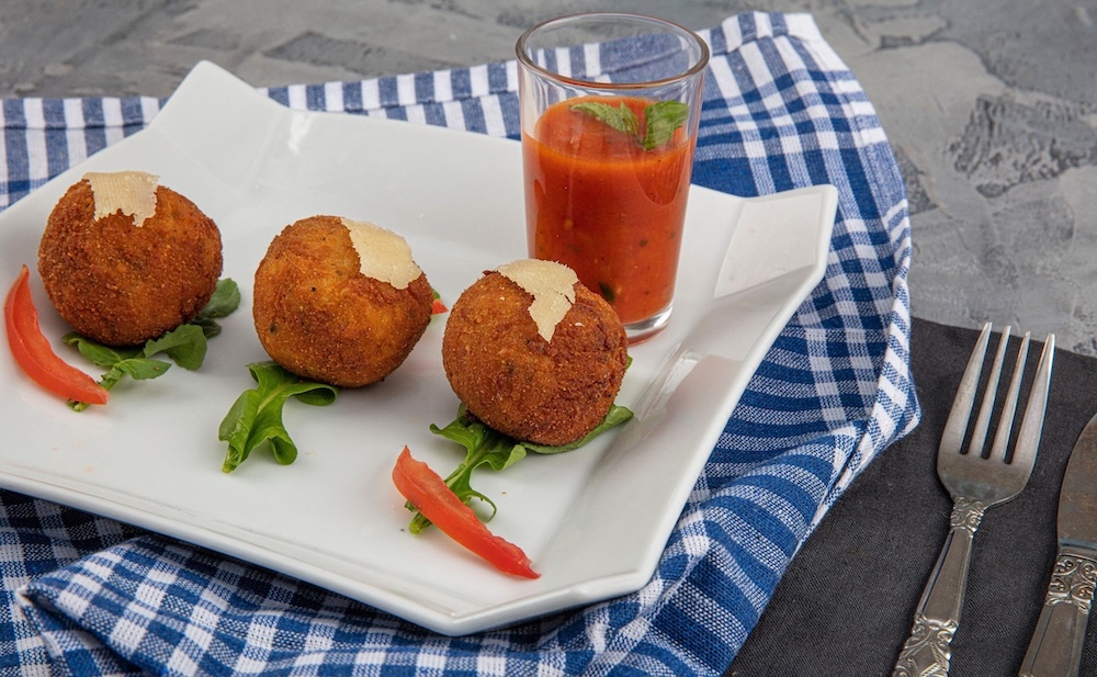 Arancini na Siciliji kot hrustljave ocvrte riževe kroglice z bogatim nadevom