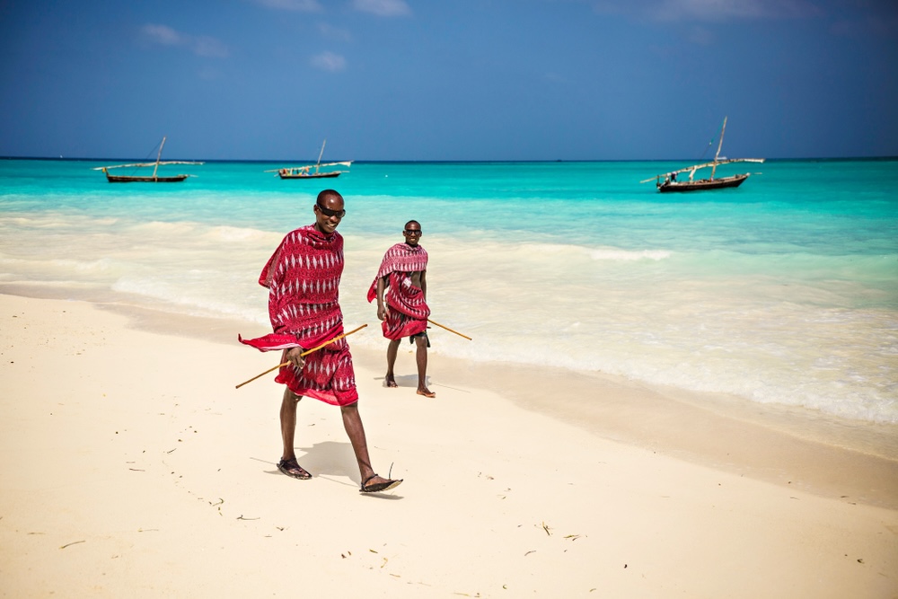 ZANZIBAR, TANZANIA - January 2018: Two Masai friends dressed in traditional clothes walking along the beach, Zanzibar, Tanzania